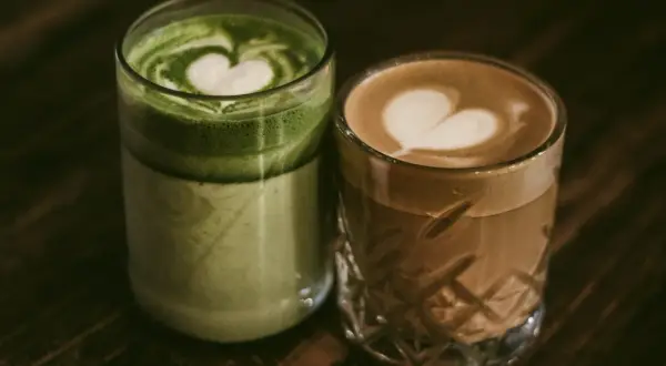 Zielone matcha latte i kawowe latte z serduszkami na piance. Dylemat: kawa czy herbata?