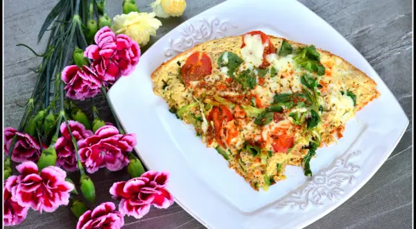 Pyszny omlet z tuńczykiem, pomidorami i zielonymi warzywami, udekorowany kwiatami.