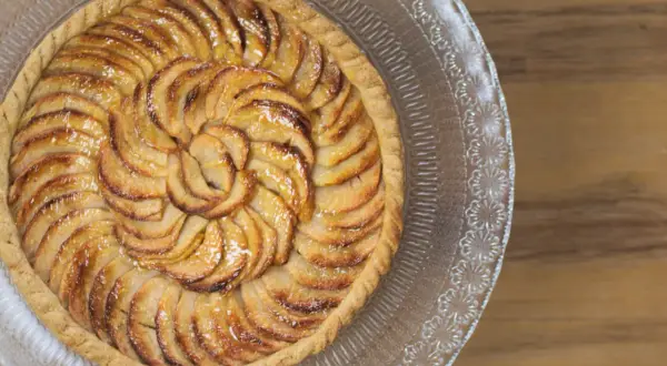 Tarte aux pommes dorée, joliment disposée en spirale. Quelle pâte pour une tarte sucrée ? Une pâte sablée croustillante serait parfaite.