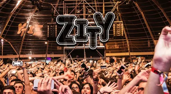 Multitud animada en la entrada del espacio Zity, con brazos en alto y móviles grabando el evento.