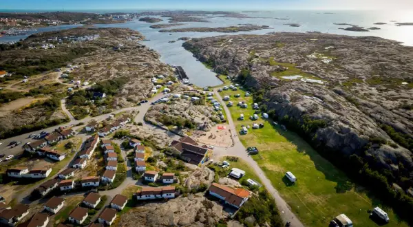 Vacker vy över Solvik first camp med stugor, husvagnar och lekplats vid havet.