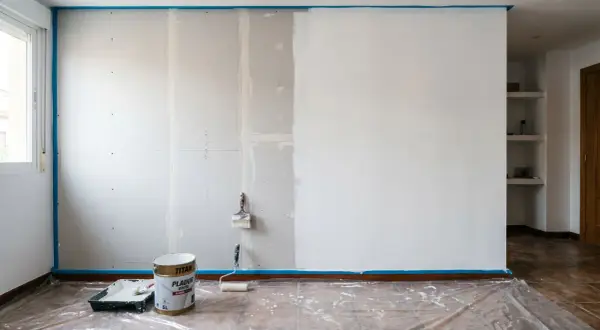 Pintando una pared de pladur. Cubo de pintura blanca, rodillo y brocha listos para transformar el espacio.