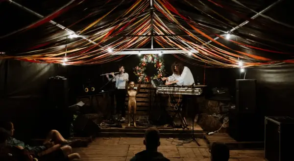 Muzycy grają na scenie pod kolorowymi wstążkami. Atmosfera jak na **grajdół festiwal**.