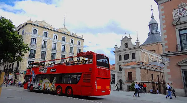 Roter Doppeldeckerbus mit Touristen fährt durch Madrid. Tolle Madrid Tipps für Sightseeing!
