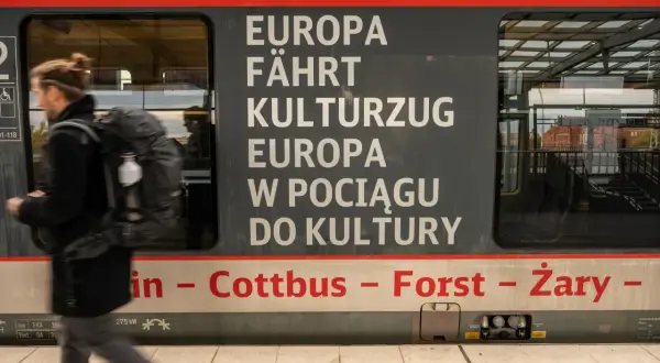 Ein Mann mit Rucksack steigt in einen Zug, der von Berlin nach Breslau fährt. Der Schriftzug "Europa fährt Kulturzug" ziert die Seite.