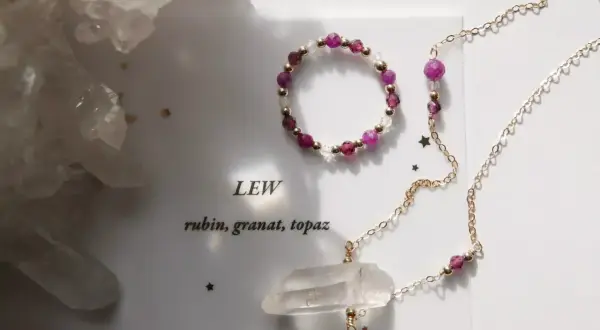Jaki kamień dla Lwa? Rubin, granat i topaz w złotej biżuterii, obok kryształów.