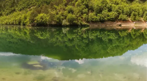Verde smeraldo del lago di Boccafornace riflette la lussureggiante vegetazione che lo circonda, creando un'immagine speculare mozzafiato.
