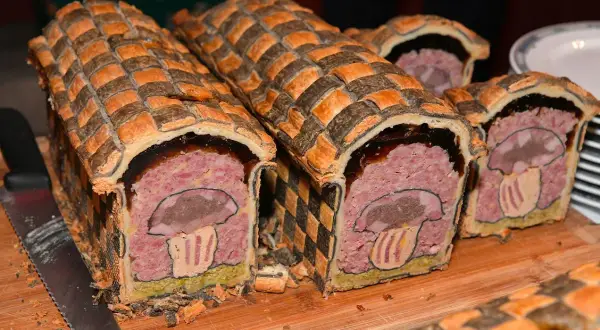Pâté en croûte d'origine, décoré d'un champignon stylisé. Une œuvre culinaire qui raconte l'histoire de ce plat traditionnel.