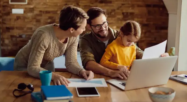 Familj planerar sin ekonomi. Pappa, mamma och dotter vid datorn, diskuterar spartips för hushållsekonomi.