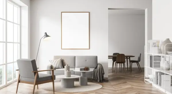 Nowoczesny salon z szarą kanapą i fotelem, stolikami kawowymi, lampą i pustą ramą na ścianie. Czy szary z beżem pasuje? Tak, tworzy przytulną atmosferę.