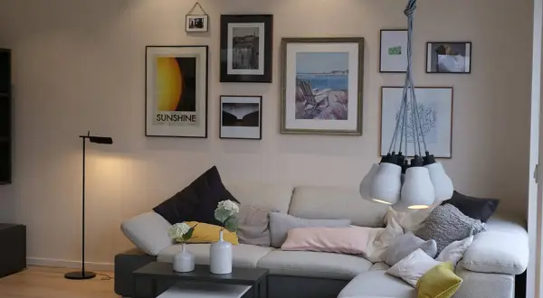 Galeria ścienna z malarstwem pejzażowym, w tym obrazem "Sunshine", tworzy przytulną atmosferę w salonie.