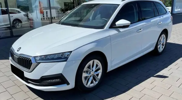 Białe, duże auto rodzinne typu kombi stoi przed salonem samochodowym. Idealne na wakacyjne wyjazdy i codzienne dojazdy.