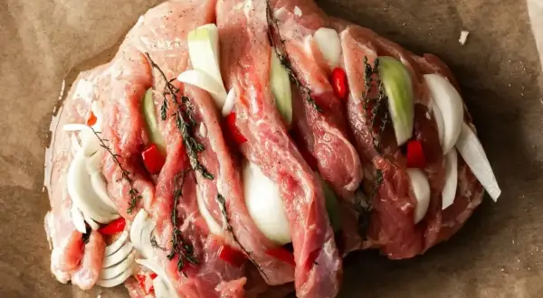 Surowa szynka z cebulą, papryczką chili i ziołami, gotowa na pyszny obiad.