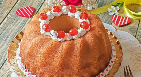 Un delicioso baba postre decorado con crema batida y cerezas rojas, listo para celebrar el amor.