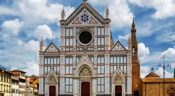 La magnifica facciata della Basilica di Santa Croce domina la piazza, con il cielo azzurro e nuvole bianche.