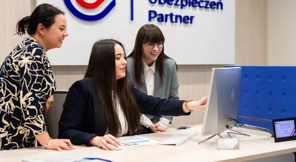 Trzy kobiety przy biurku analizują dane na komputerze.