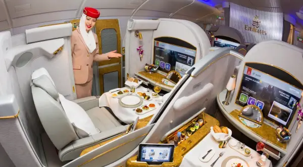 Stewardessa Emirates wita pasażera w luksusowej kabinie, oferując posiłek i rozrywkę. To szczyt komfortu podróży, oferowany przez jedne z największych linii lotniczych.