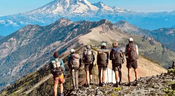 Sześcioro turystów z plecakami na grani, podziwiających majestatyczny szczyt. Przygoda na Pacific Crest Trail trwa.