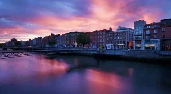 Zachód słońca nad rzeką Liffey w Dublinie. Warto zobaczyć te malownicze budynki i most w różowych barwach nieba.