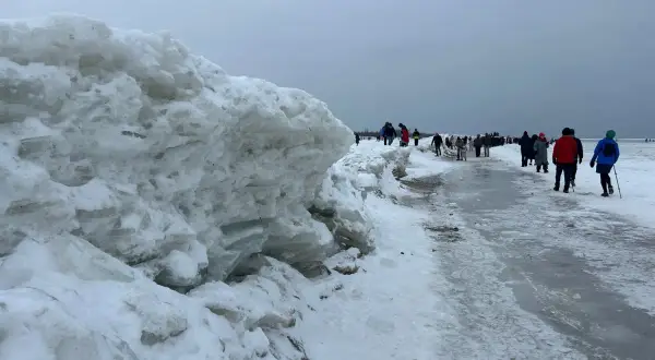 Mikoszewo: imponujące góry lodowe na plaży, ludzie spacerują po zamarzniętym brzegu.