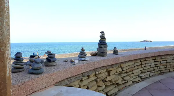 Torres de piedras en el **carboneras paseo marítimo**. El mar azul y el cielo despejado crean un fondo sereno para estas esculturas efímeras.