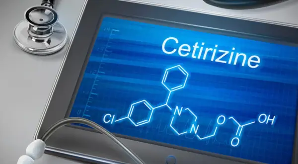 Tablet z ekranem wyświetlającym wzór chemiczny cetyryzyny i stetoskop.