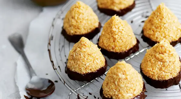Kokostoppar recept: konfekt med kokos och choklad på ett galler. En sked med choklad ligger bredvid.