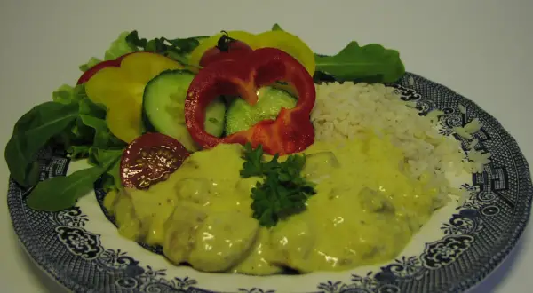En tallrik med ris, kyckling i krämig currysås, sallad och grönsaker. Ett perfekt currysås recept för en god middag.