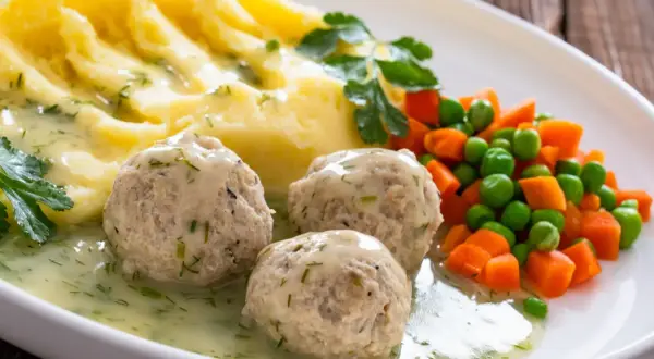 Kotlety mielone w sosie, puree ziemniaczane i warzywa na talerzu.