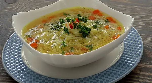 Aromatyczna zupa na rosole z makaronem nitki i marchewką, udekorowana natką pietruszki. Idealna na chłodne dni.