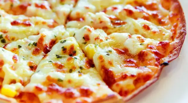 Pyszna, gorąca pizza z patelni, z ciągnącym się serem i ziołami, gotowa do podania.