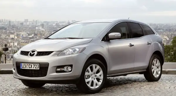 Srebrna Mazda CX-7 2.3 Turbo na tle panoramy miasta.