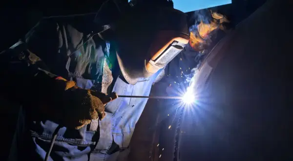 Spawacz w masce ochronnej spawa rurę, używając elektrody. Zastanawiasz się, jaka elektroda do stali 2mm?