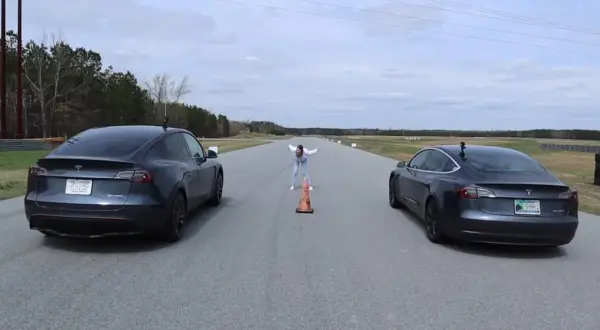 Dwa modele Tesla Model 3 i Model Y stoją na torze wyścigowym, gotowe do startu.