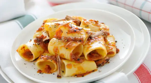 Une assiette de paccheri généreusement nappés d'une sauce tomate riche et de morceaux de viande savoureux. Ce plat de pâtes à la viande est un délice réconfortant.