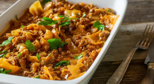 Herzhaftes Schichtkohl mit Hackfleisch, ein beliebtes DDR Rezept, serviert in einer weißen Auflaufform, garniert mit Petersilie.