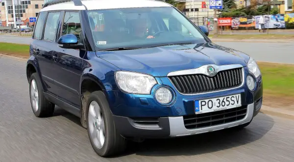 Niebieska Skoda Yeti na drodze. Kierowca w środku. Wiele pozytywnych skoda yeti opinie o tym modelu.