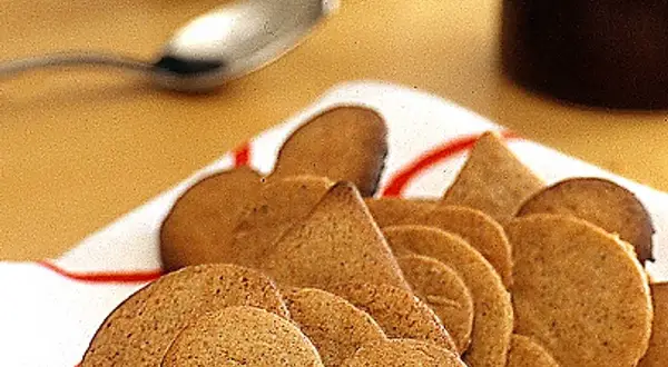 En hög med pepparkakor, perfekta att förvara till jul. En sked ligger redo för att njuta av dem.