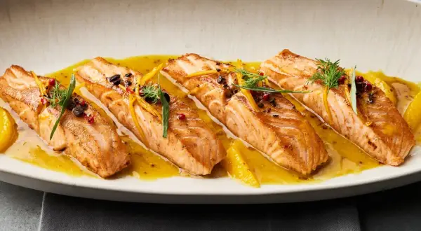 Gebratene Lachsfilets auf einer Zitrussoße, garniert mit Dill und Orangenzesten. Tolle Ideen für eine Fischplatte!