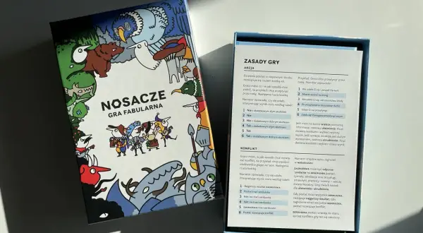 Pudełko gry fabularnej "Nosacze" z kolorowymi ilustracjami i otwartą instrukcją.