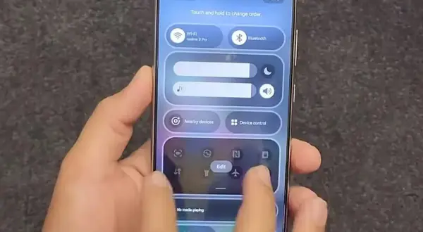 Dłoń steruje smartfonem z interfejsem One UI, pokazując panel szybkich ustawień z Wi-Fi, Bluetooth i innymi opcjami.