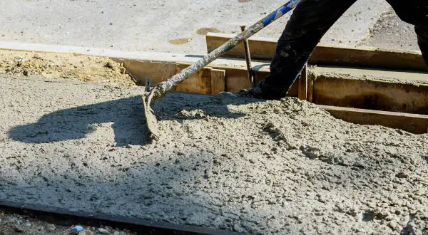 Pracownik rozprowadza świeży beton c30/37 za pomocą łopaty.