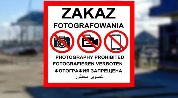 Znak ZAKAZ FOTOGRAFOWANIA z ikonami aparatu, kamery i telefonu komórkowego w czerwonych okręgach.