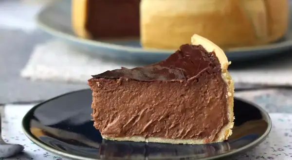 Rebanada de flan de chocolate con cobertura brillante, servida en plato oscuro.