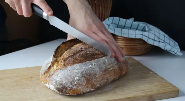 Krojenie świeżo upieczonego chleba na desce. Idealny przepis na chleb dla każdego.