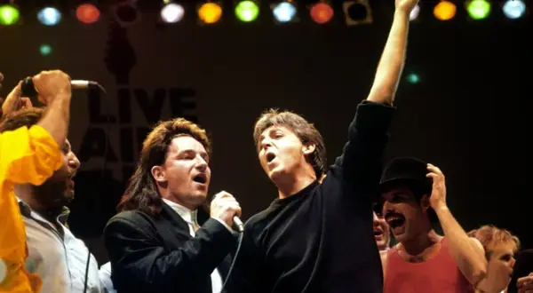 Bono und Paul McCartney singen bei Live Aid. Freddie Mercury jubelt im Hintergrund. Legendäre Live Aid Bands vereint.