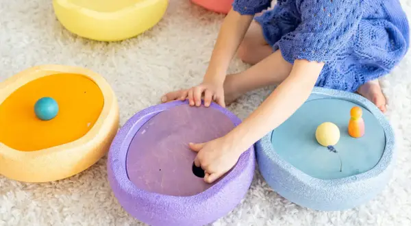 Kind spielt mit bunten Stapelsteinen und erforscht verschiedene Stapelsteine Spielideen.