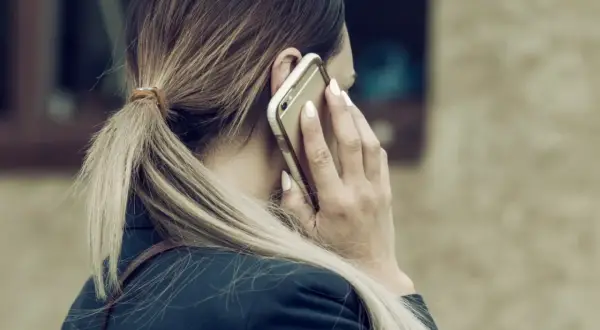 Kobieta rozmawia przez telefon, martwiąc się, czy pracodawca może odmówić urlopu na żądanie.