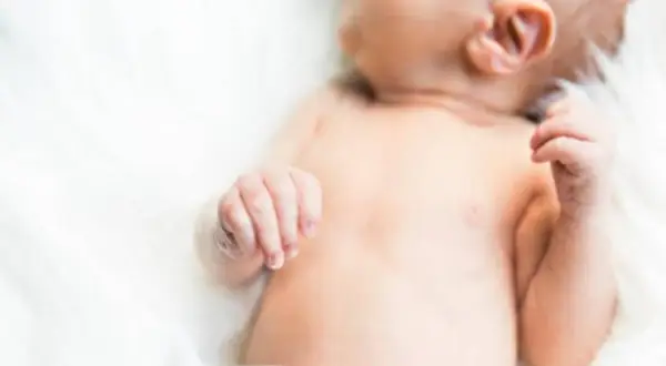 Delikatna skóra niemowlęcia, być może zmagającego się z trądzikiem niemowlęcym lub skazą białkową, na białym tle.