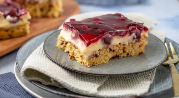 Ein Stück saftige Kirschtorte mit Pudding und Kirschen, bedeckt mit rotem Tortenguss.